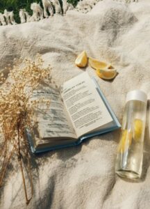 Open book, citrus slices, and glass of water on beige fabric in natural light