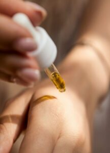Close-up of hand applying skincare serum with a glass dropper